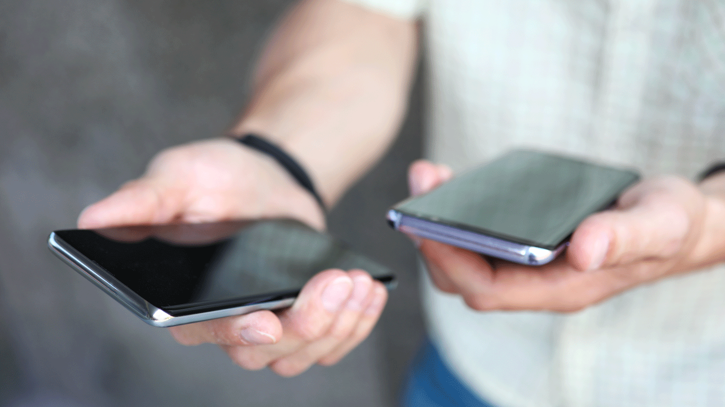 Person mit zwei Smartphone Telefonen in der Hand.