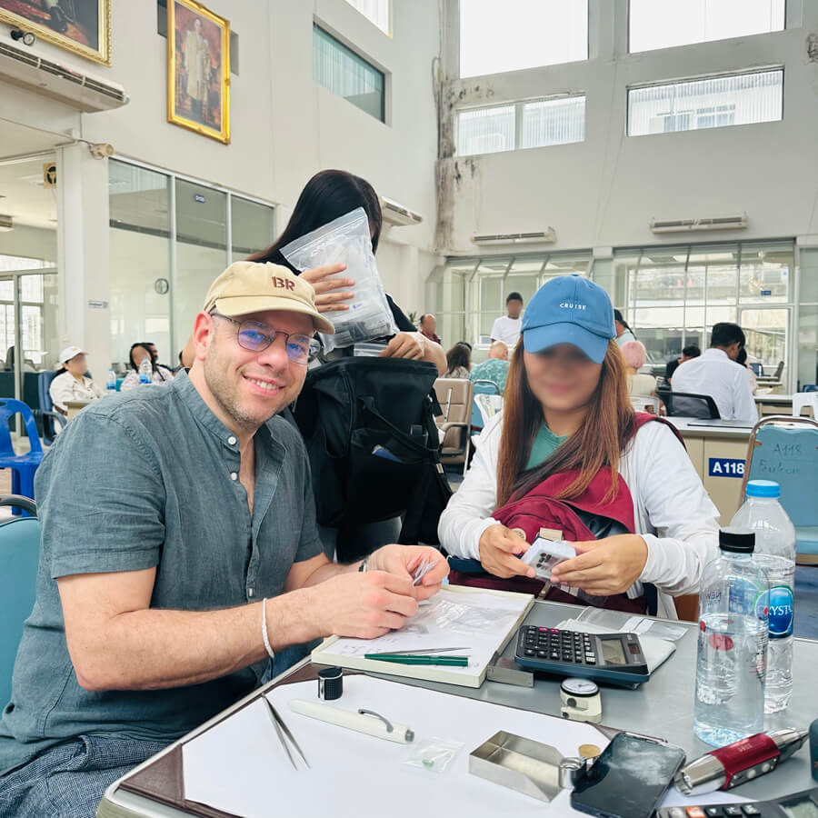 Tisch zum Edelsteinkauf in Chanthaburi, Thailand: Man sieht den Gemmologen beim Ansehen von Steinen mit einer Edelstein-Brokerin