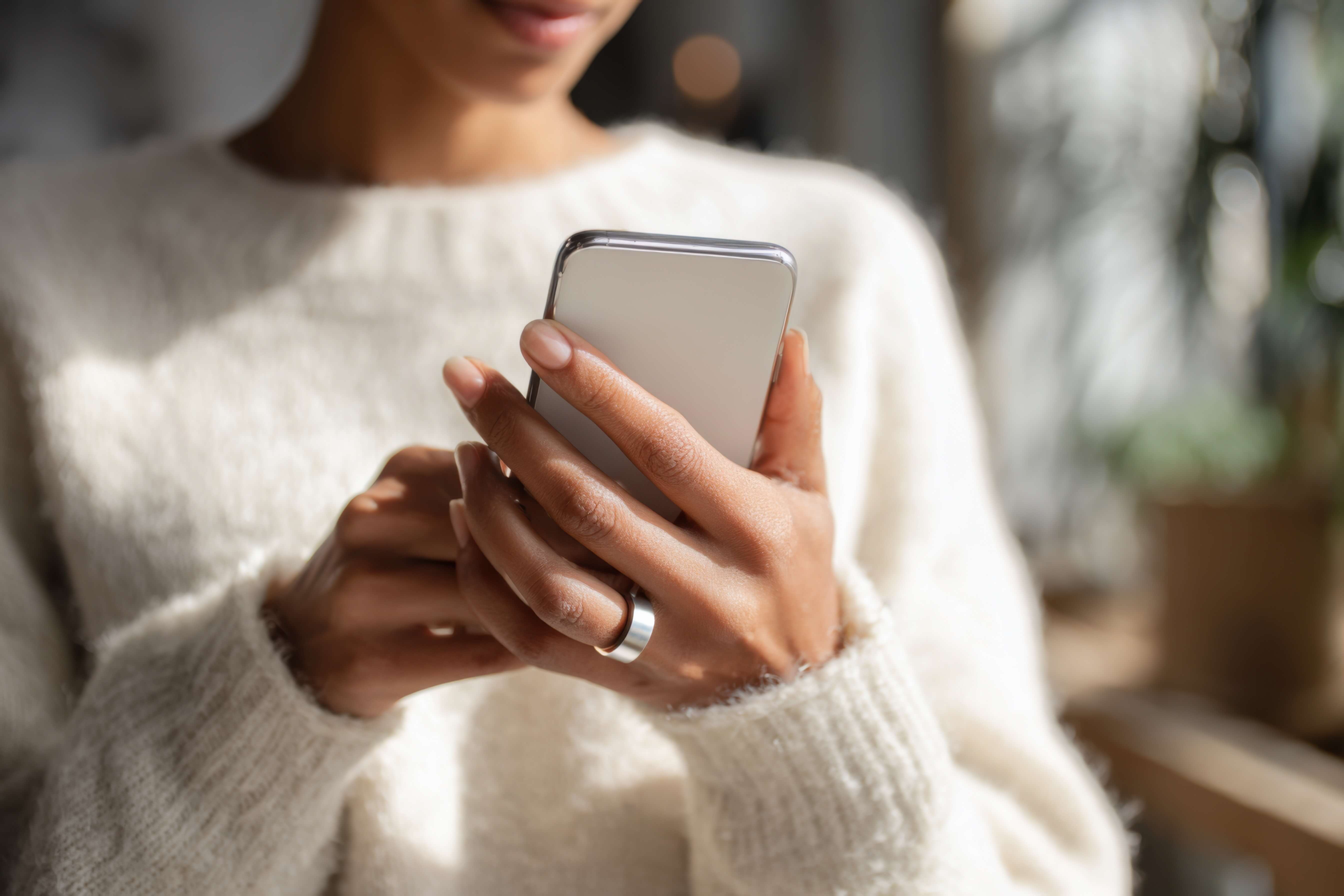 Smart-Ringe: Person hält Smartphone in den Händen und trägt Smart Ring am Finger