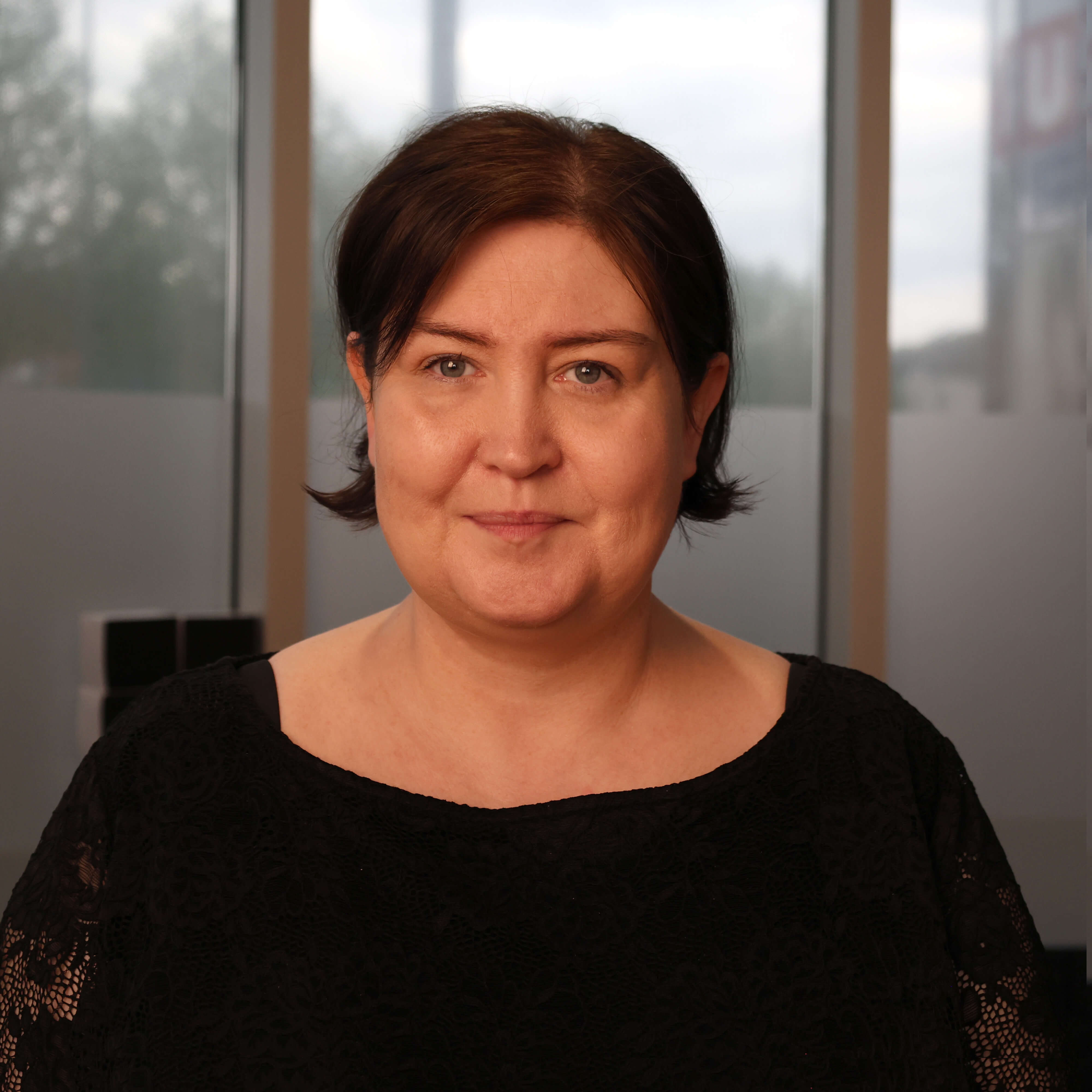 filialleiterin-vor-dem-fenster-in-warmem-licht-an-einem-bewoelkten-tag