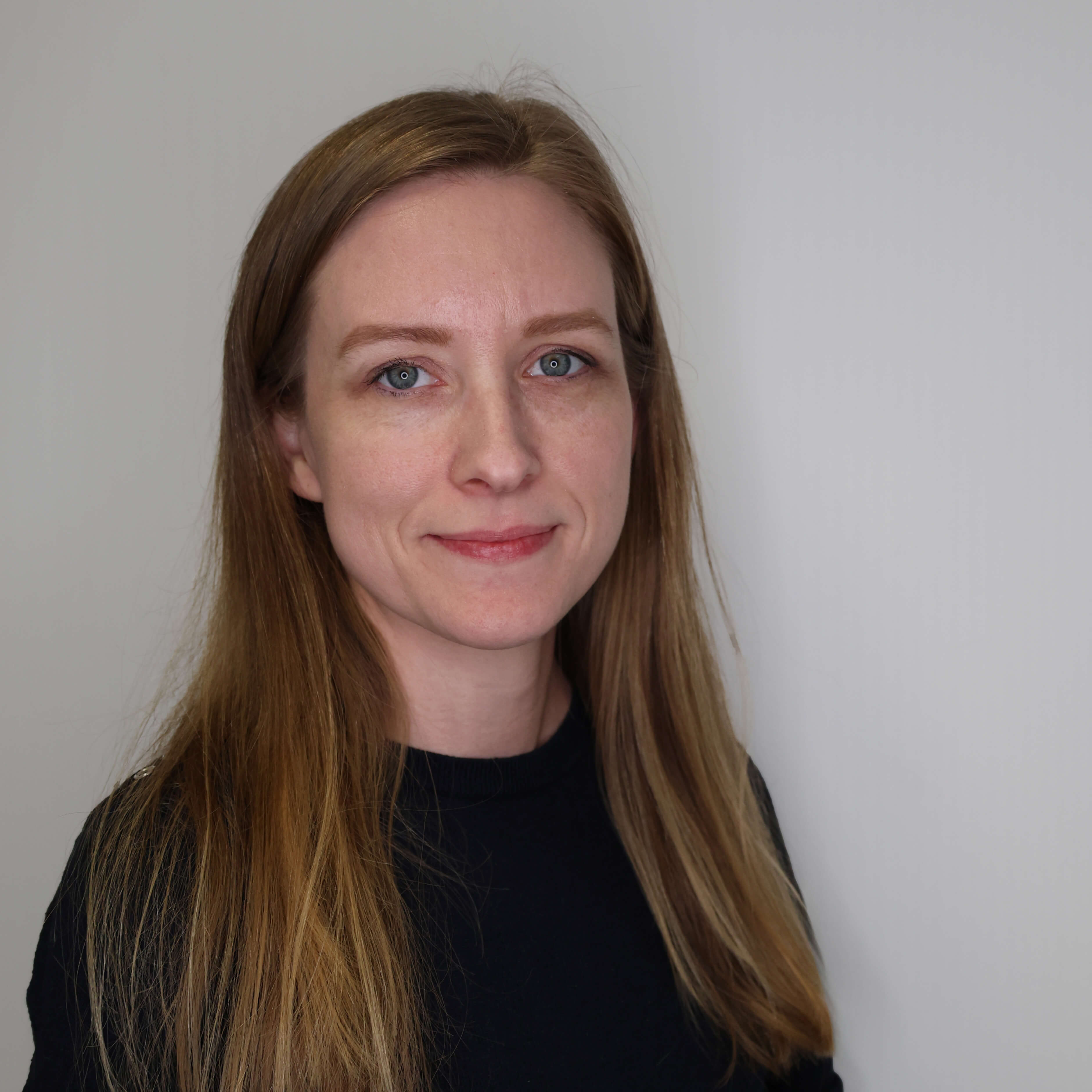 filialleiterin-in-einem-schwarzen-shirt-vor-einer-grauen-wand