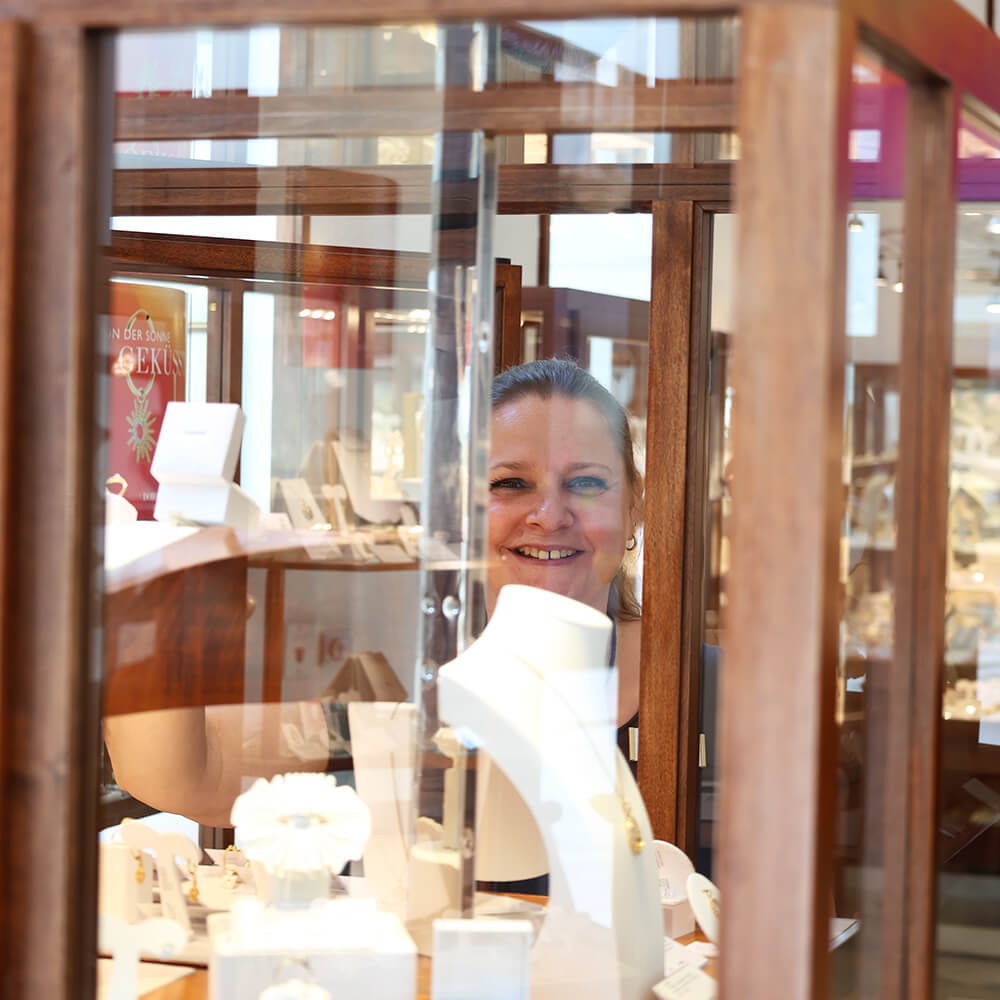 filialleiterin-hinter-einer-vitrine-laechelnd-durch-das-glas