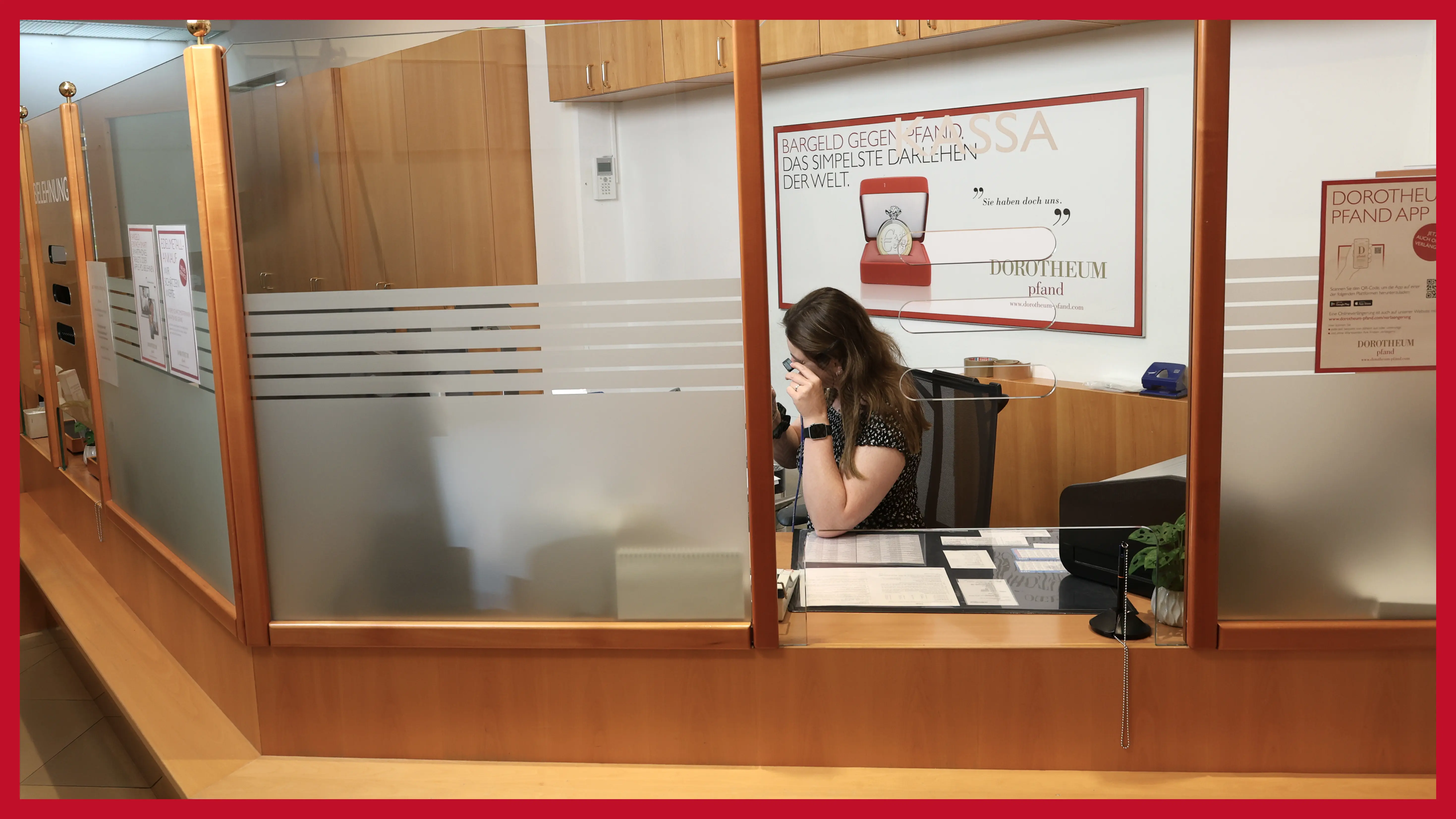 schaetzmeisterin-hinter-einem-schalter-begutachtet-einen-wertgegenstand-mit-einer-juewlier-lupe