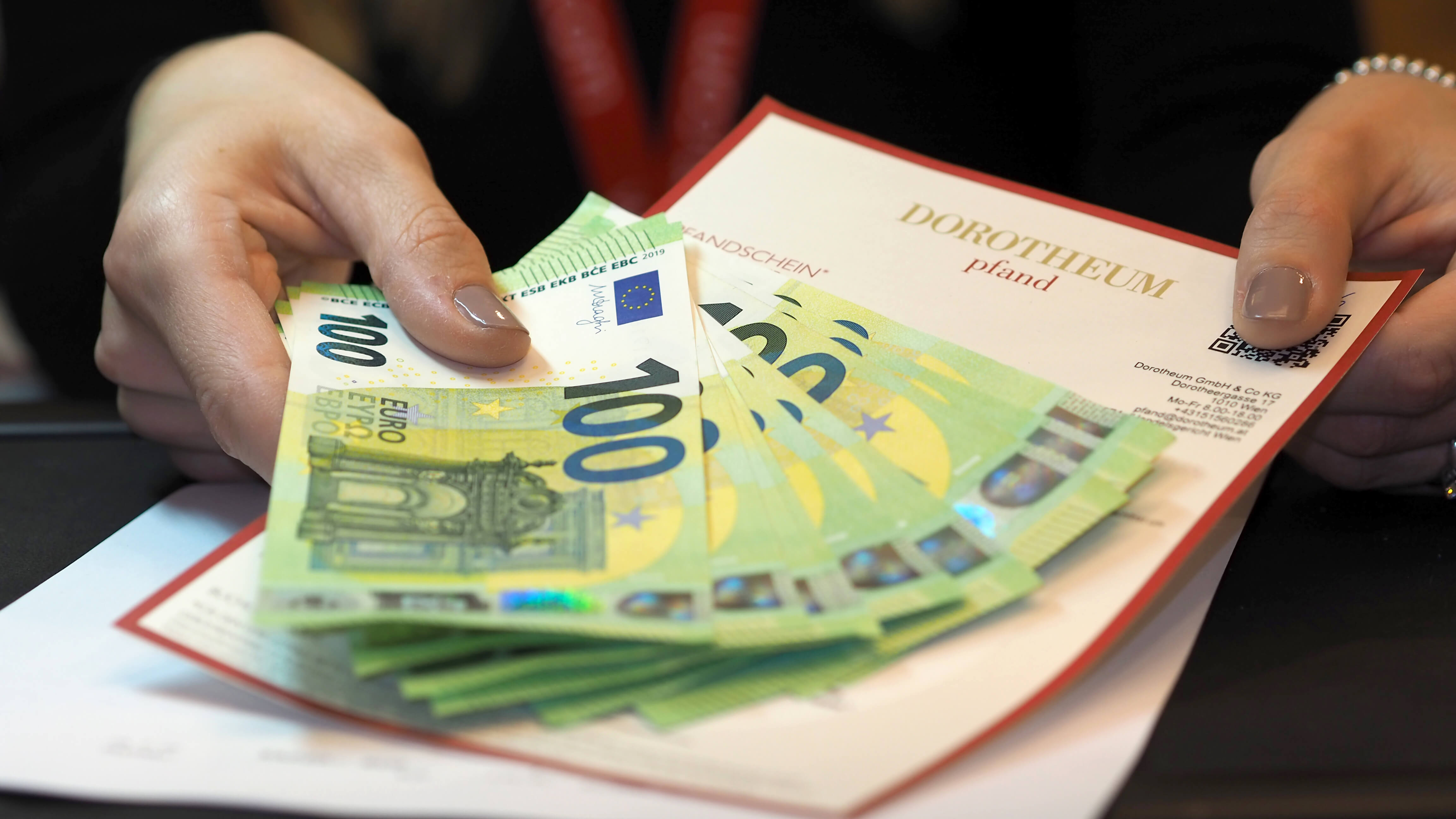 Pfanddarlehen Geldscheine und Pfandschein in einer Damenhand