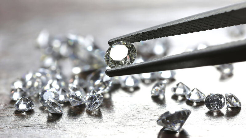 Anlagediamanten -Brillant in Pinzette- Diamanten im Hintergrund