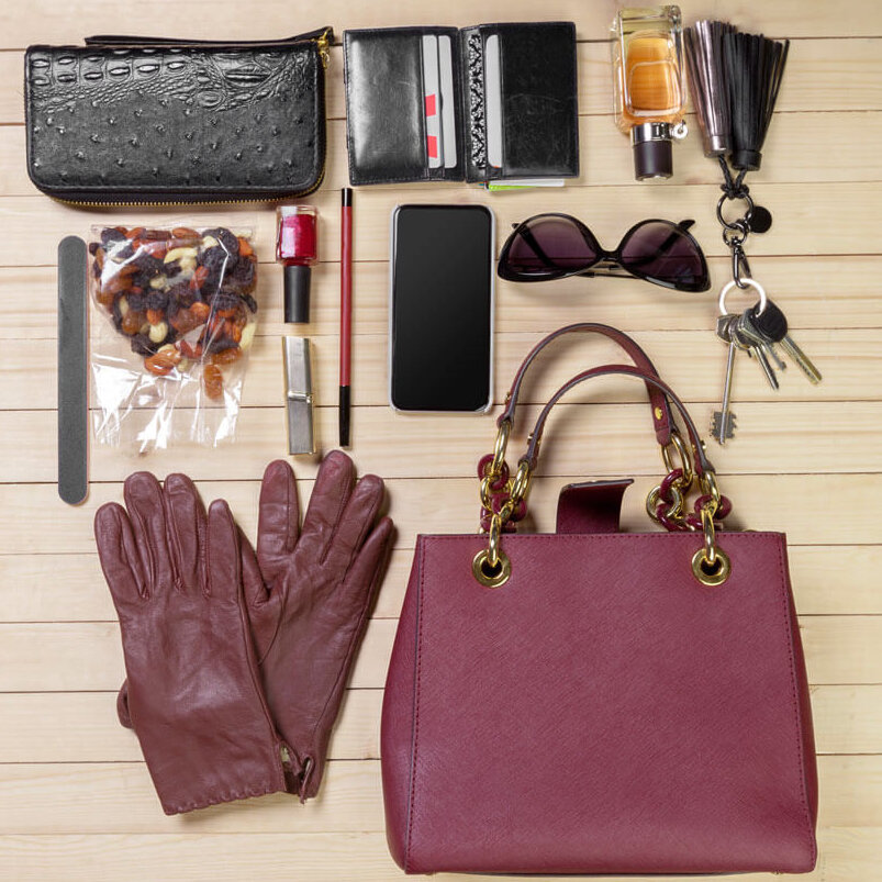 Übersicht eines Tascheninhalts einer roten Damen Luxus Handtasche mit make-up, Parfum und anderen gegenständen