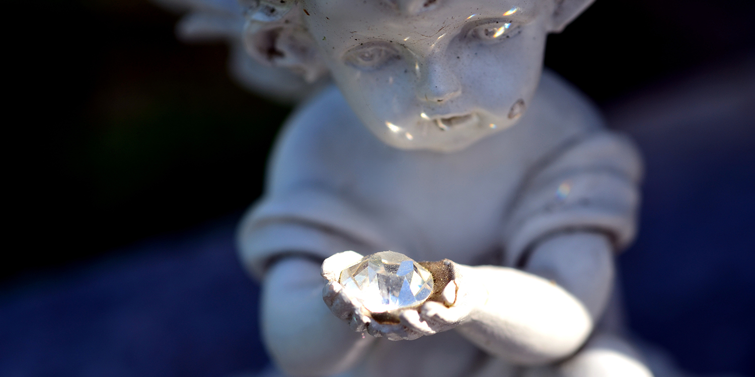 Diamantbestattung - Engel aus Stein hält Edelstein in Händen